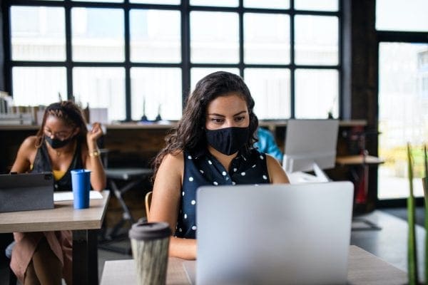 Business woman with face mask indoors in office, back to work after coronavirus lockdown