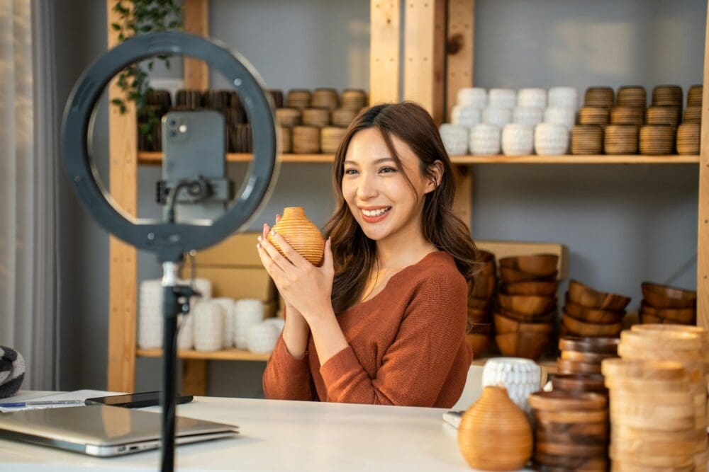 Asian young woman selling vase product online live streaming at home.