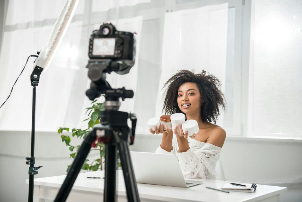 selective focus of attractive african american influencer in braces holding containers with cosmetic